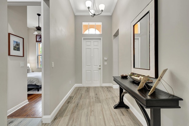 entryway with crown molding, ceiling fan with notable chandelier, and light hardwood / wood-style floors