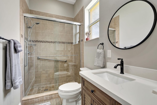 bathroom with a shower with door, vanity, and toilet