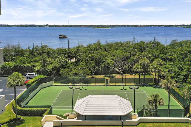 exterior space with tennis court and a water view