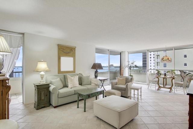 living room with a water view, a textured ceiling, and a wall of windows