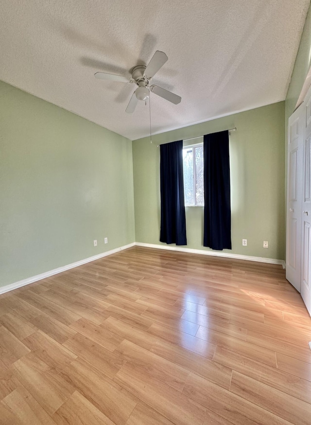 empty room with ceiling fan, a textured ceiling, and light hardwood / wood-style floors