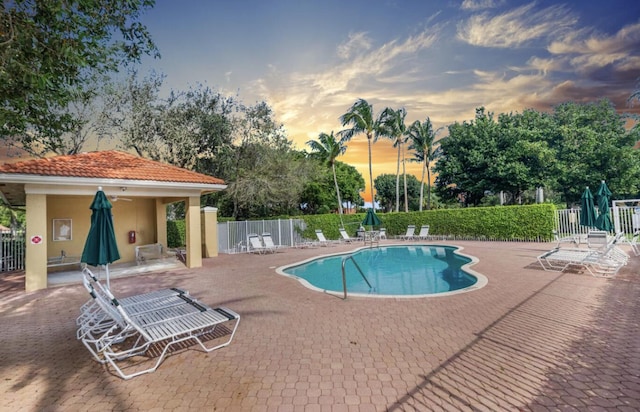 pool at dusk featuring a patio