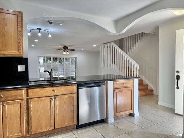 kitchen with dishwasher, sink, light tile patterned flooring, and dark stone counters