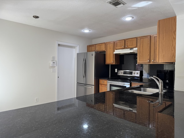 kitchen featuring appliances with stainless steel finishes, sink, dark stone countertops, and a textured ceiling