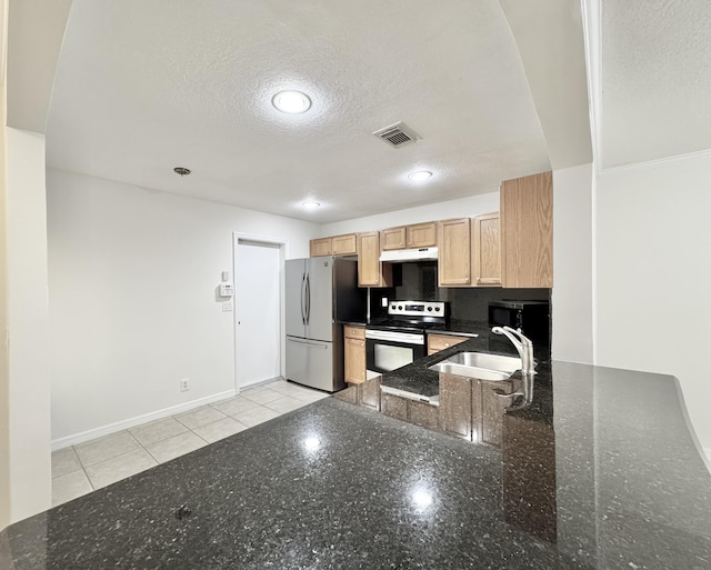 kitchen with stainless steel appliances, sink, a textured ceiling, dark stone counters, and light brown cabinets