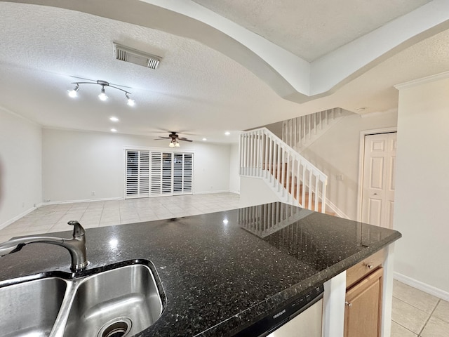 kitchen with light tile patterned flooring, sink, dark stone counters, and a textured ceiling