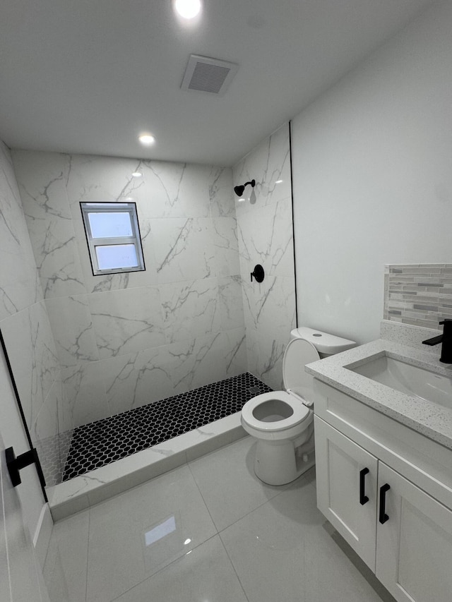 bathroom with vanity, toilet, and a tile shower