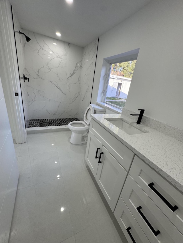 bathroom featuring tiled shower, vanity, and toilet