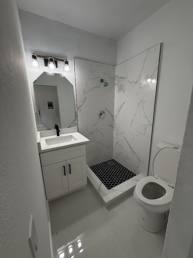 bathroom with vanity, tiled shower, and toilet