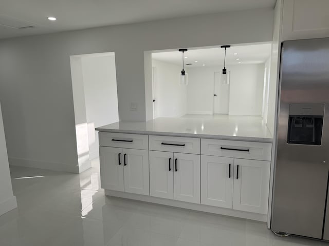 interior space with pendant lighting, white cabinets, light stone counters, and stainless steel fridge with ice dispenser