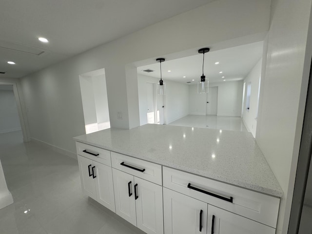 kitchen featuring decorative light fixtures, light stone countertops, and white cabinets