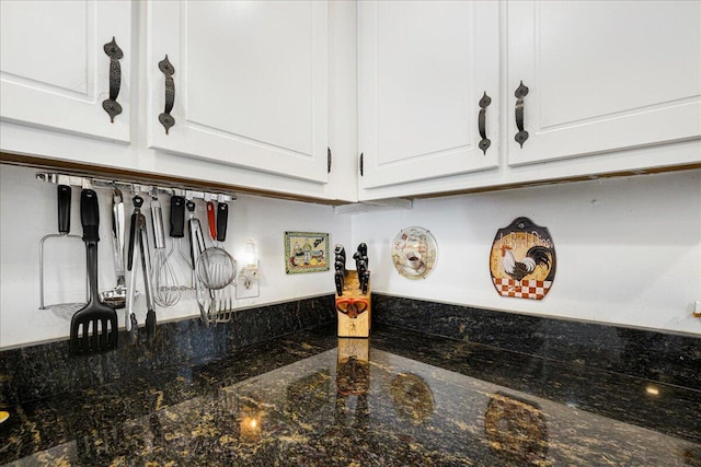 room details featuring dark stone countertops and white cabinets