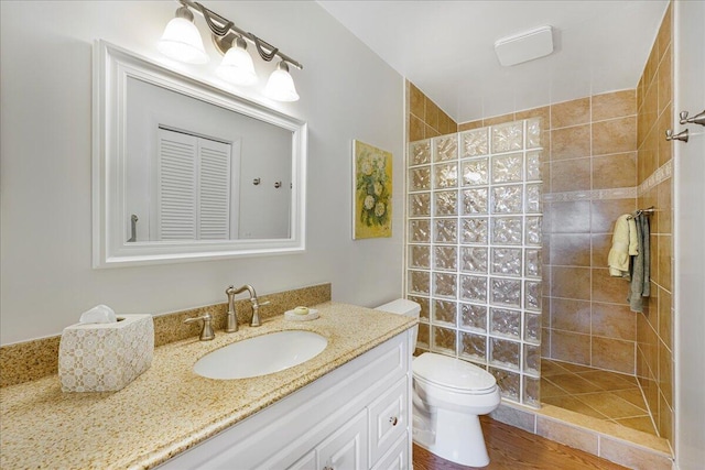 bathroom with tiled shower, vanity, and toilet