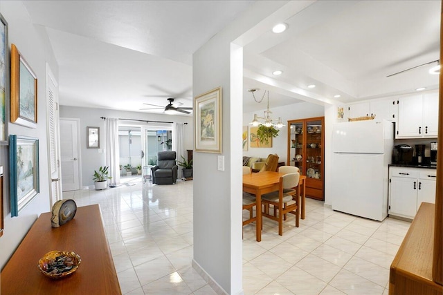 interior space featuring white refrigerator, white cabinetry, light tile patterned floors, and pendant lighting