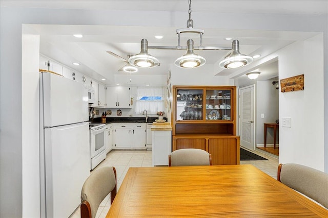 kitchen featuring decorative light fixtures, sink, white cabinets, light tile patterned floors, and white appliances