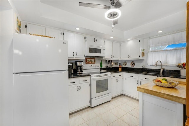 kitchen featuring sink, white appliances, ceiling fan, white cabinetry, and a raised ceiling