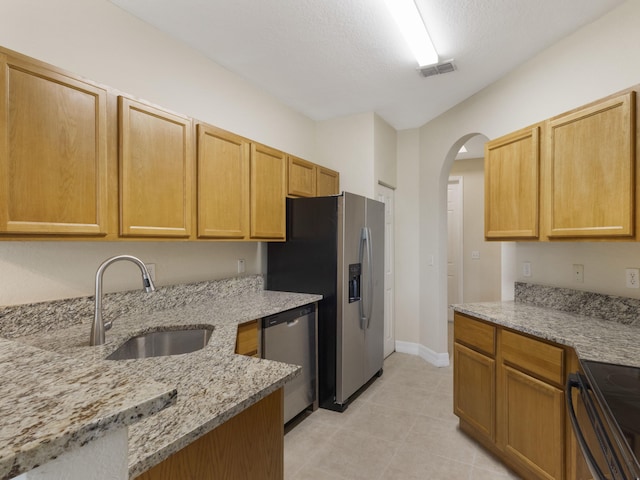 773 Pipers Cay Dr, West Palm Beach, FL 33415 - kitchen with stainless steel appliances, a sink, arched walkways, light stone countertops, and baseboards
