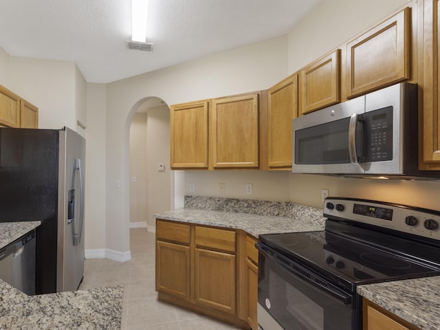 773 Pipers Cay Dr, West Palm Beach, FL 33415 - kitchen with appliances with stainless steel finishes, arched walkways, light tile patterned floors, and light stone countertops