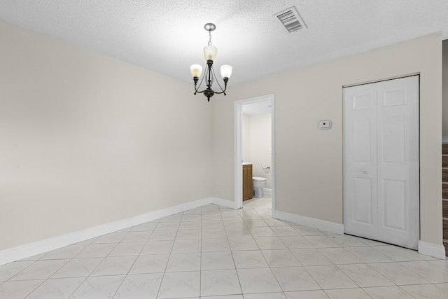 spare room with light tile patterned flooring, a notable chandelier, and a textured ceiling