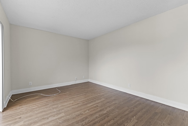 spare room featuring wood-type flooring and a textured ceiling