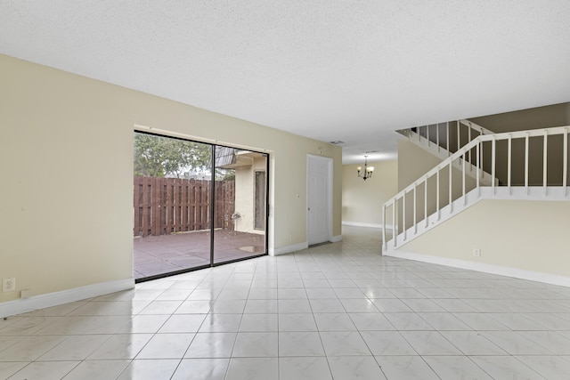 tiled empty room with a chandelier and a textured ceiling