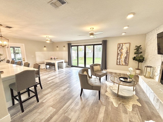 living room with a healthy amount of sunlight, a fireplace, a textured ceiling, and light hardwood / wood-style flooring