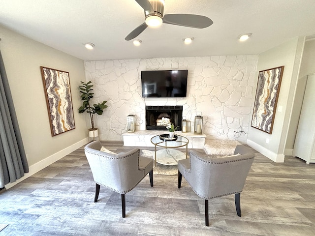 living room with a fireplace, wood-type flooring, and ceiling fan