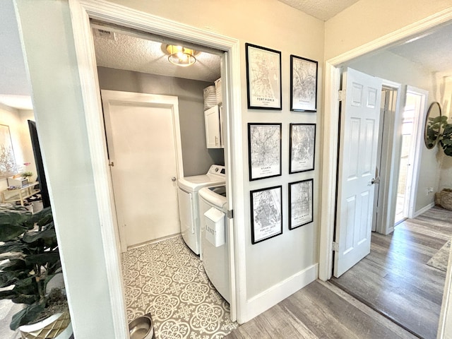 clothes washing area featuring cabinets, a textured ceiling, independent washer and dryer, and light hardwood / wood-style flooring