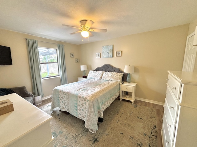 bedroom with hardwood / wood-style flooring, ceiling fan, and a textured ceiling