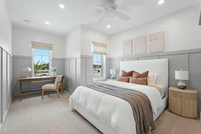 bedroom with light carpet, recessed lighting, and wainscoting