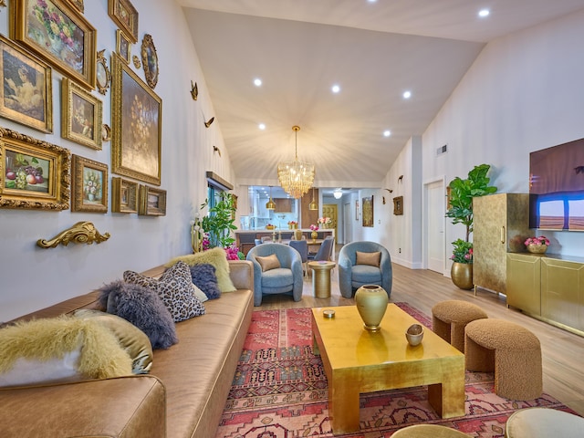 living room with high vaulted ceiling, light hardwood / wood-style flooring, and a notable chandelier