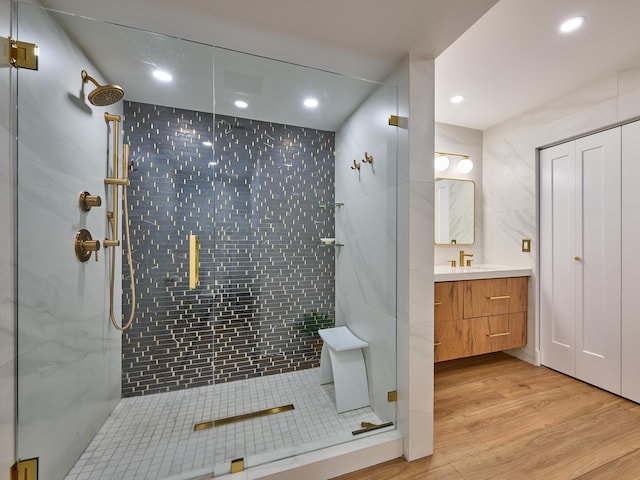 bathroom with vanity, hardwood / wood-style floors, an enclosed shower, and tile walls