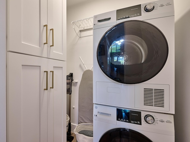 washroom with cabinets and stacked washer / drying machine