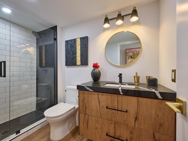 bathroom with hardwood / wood-style flooring, vanity, tiled shower, and toilet