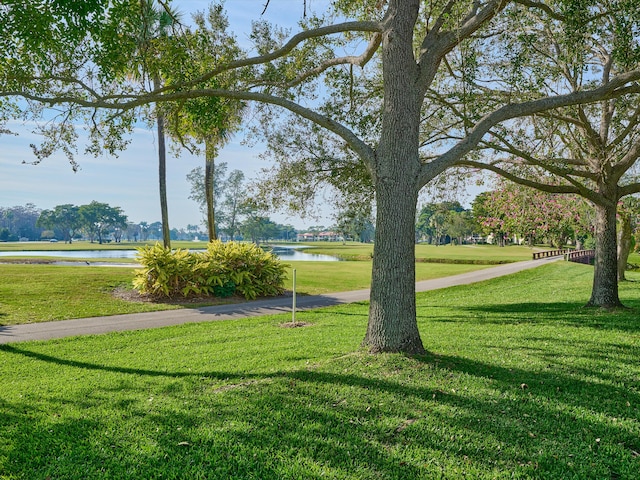 surrounding community with a water view and a yard