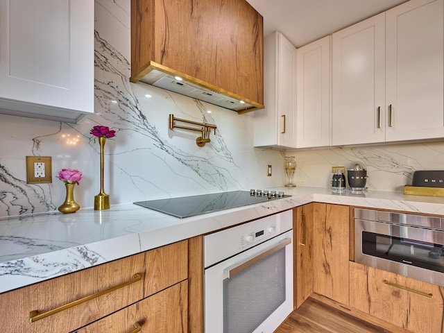 kitchen featuring tasteful backsplash, oven, black electric stovetop, and white cabinets