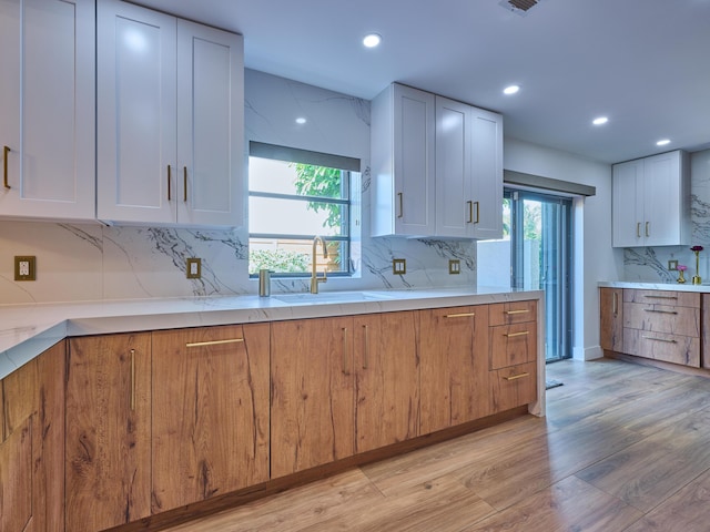 kitchen with white cabinetry, sink, light hardwood / wood-style flooring, and tasteful backsplash