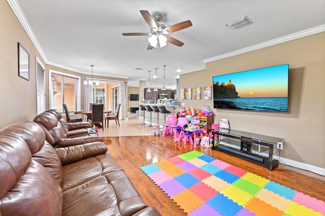 living room with crown molding, ceiling fan with notable chandelier, a textured ceiling, and light wood-type flooring