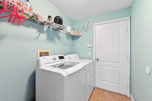 laundry room with washer and dryer, a textured ceiling, and light tile patterned flooring