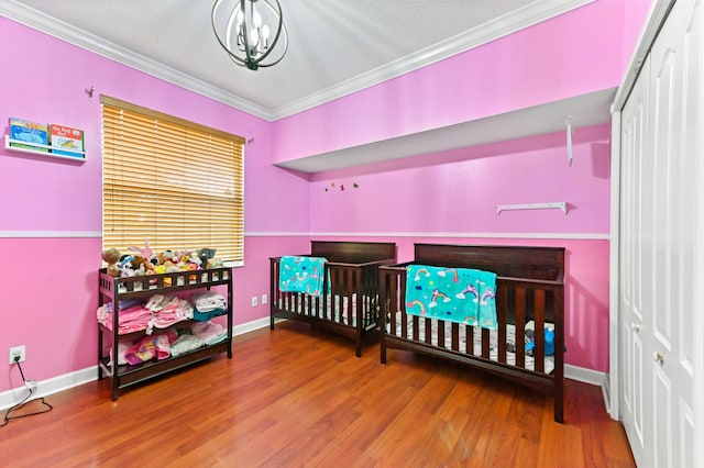 bedroom with wood-type flooring, ornamental molding, and a chandelier