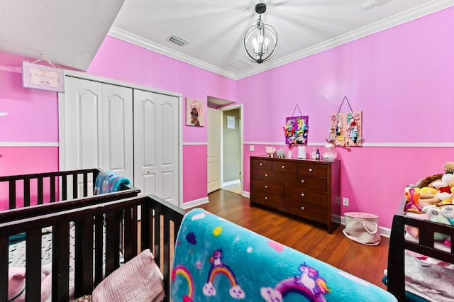 bedroom with ornamental molding, an inviting chandelier, dark hardwood / wood-style flooring, and a closet