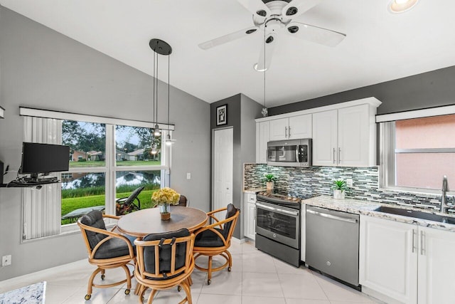 kitchen with pendant lighting, sink, appliances with stainless steel finishes, light stone counters, and white cabinets