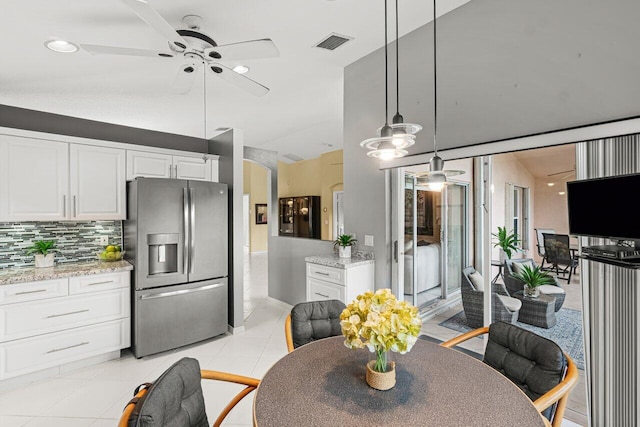 kitchen with decorative light fixtures, white cabinets, stainless steel fridge, light tile patterned floors, and light stone countertops