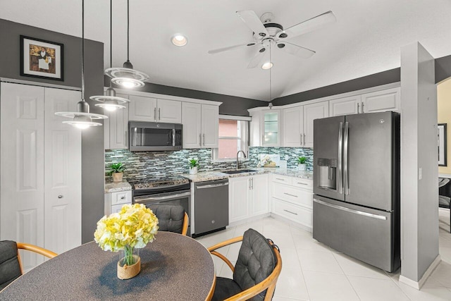 kitchen with appliances with stainless steel finishes, pendant lighting, white cabinetry, sink, and light stone countertops