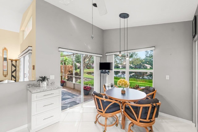 tiled dining area with a towering ceiling, plenty of natural light, and ceiling fan