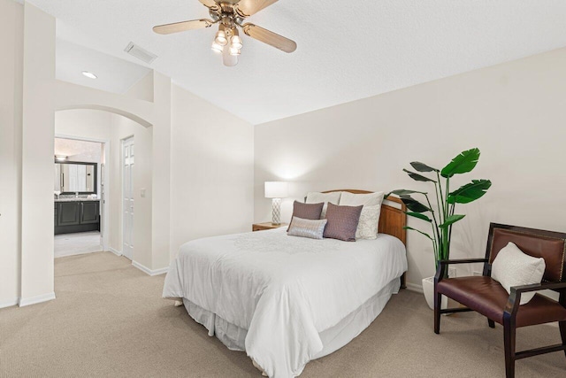 bedroom with ceiling fan, connected bathroom, vaulted ceiling, and light carpet