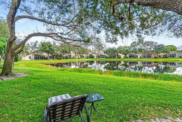 view of property's community with a water view and a lawn