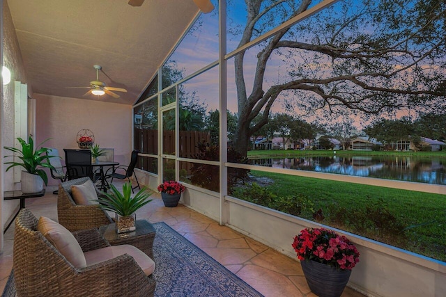 sunroom featuring lofted ceiling, ceiling fan, and a water view