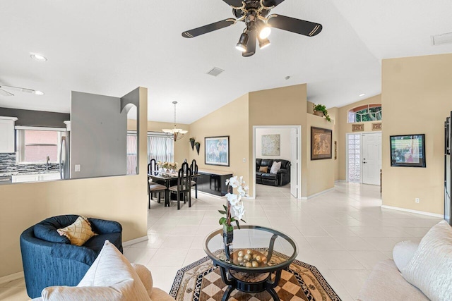 living room with lofted ceiling, light tile patterned floors, and ceiling fan with notable chandelier