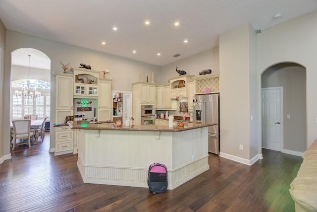 kitchen with cream cabinetry, stainless steel appliances, a breakfast bar, and a large island with sink